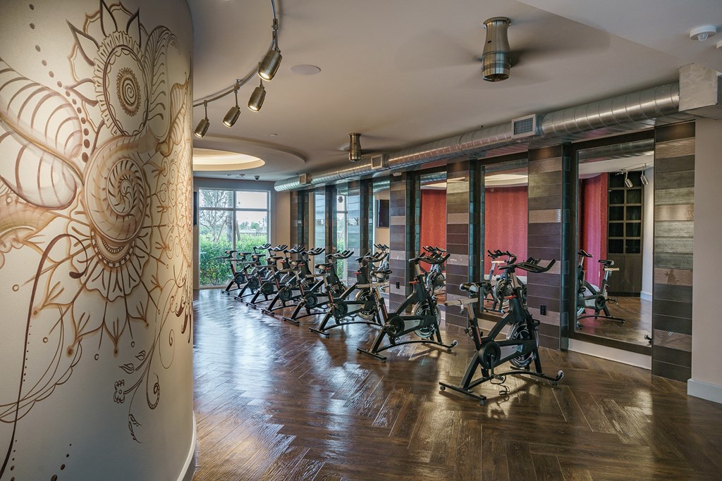 a row of exercise bikes in a room with a mural on the wall