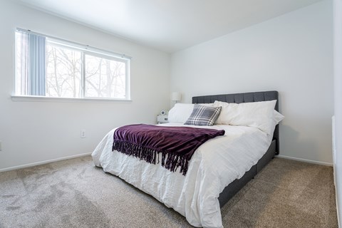 A bedroom with a large bed and a window.