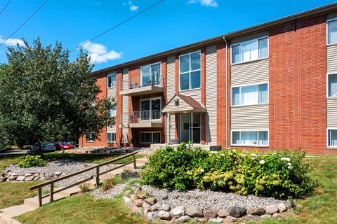 A red brick building with a landscaped front yard.