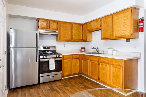 A kitchen with wooden cabinets and a stainless steel refrigerator.