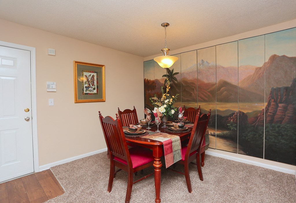 a dining room with a table and chairs and a painting on the wall