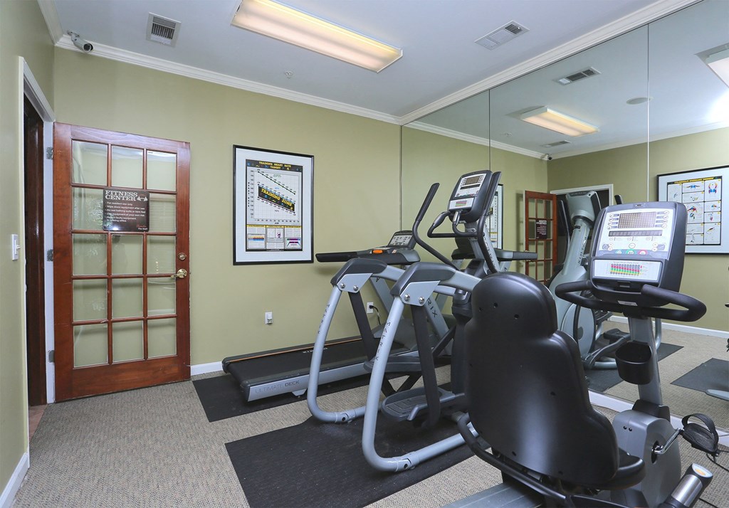 a gym with cardio equipment and mirrors on the wall