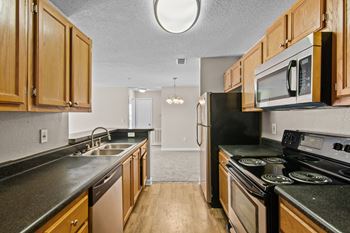 an empty kitchen with wood cabinets and black counter tops and appliances