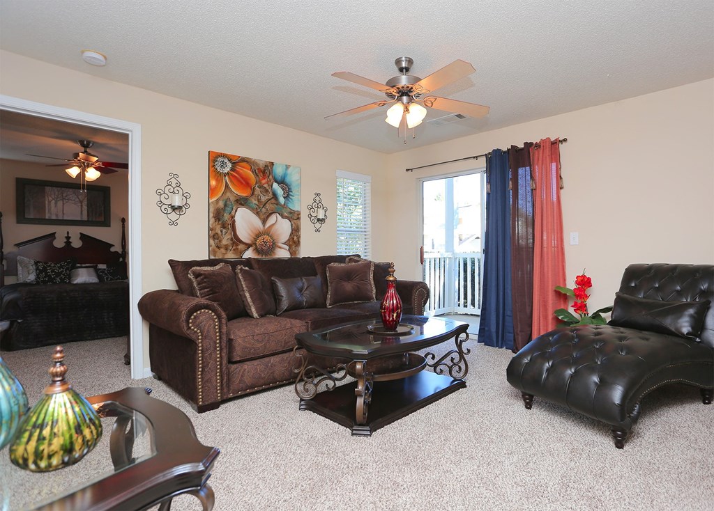 a living room with leather furniture and a ceiling fan