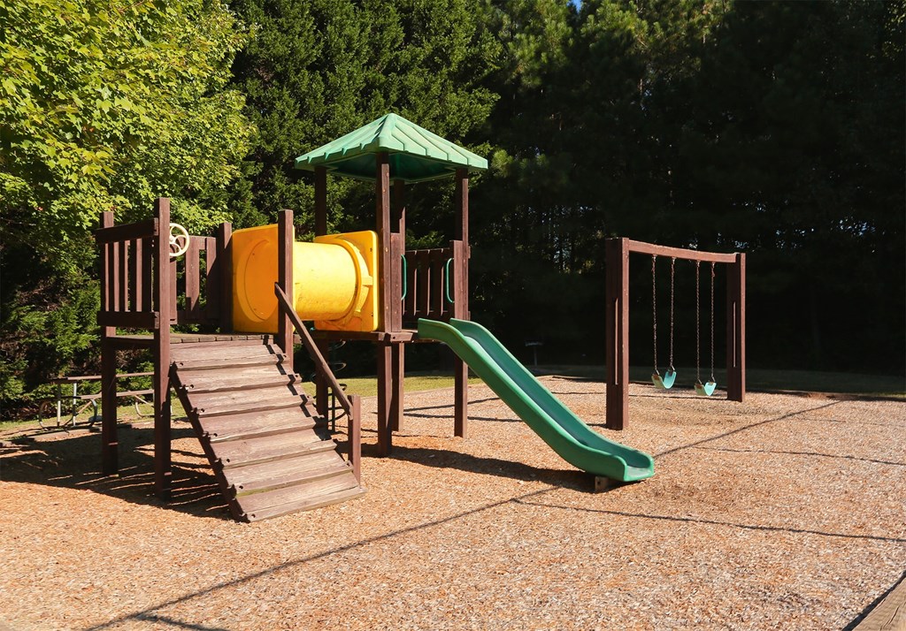 a playground with a yellow slide and a green slide