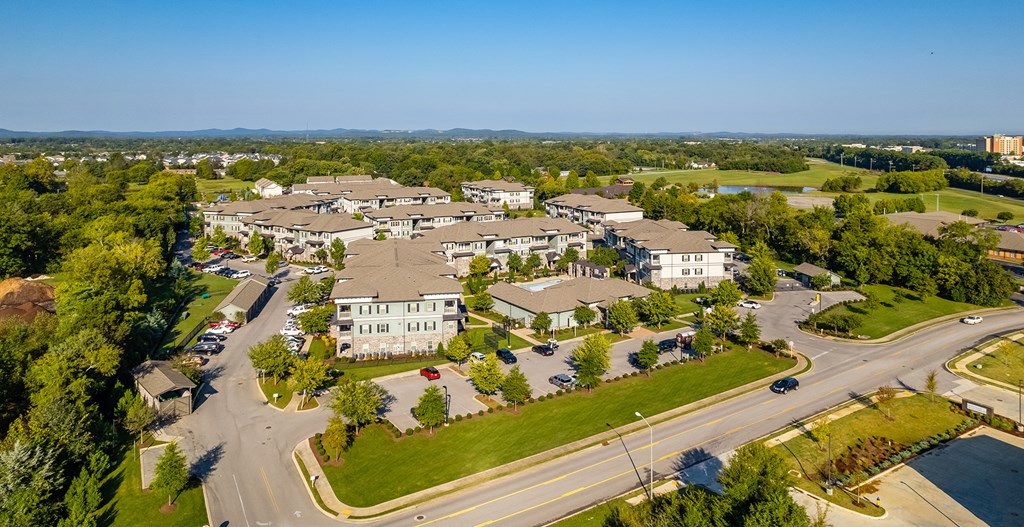 an aerial view of a neighborhood of houses with trees and a highway