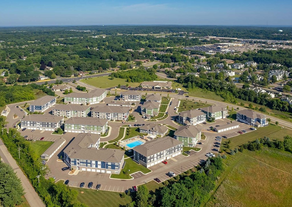 A bird's eye view of a residential area with houses, roads, and a pond.