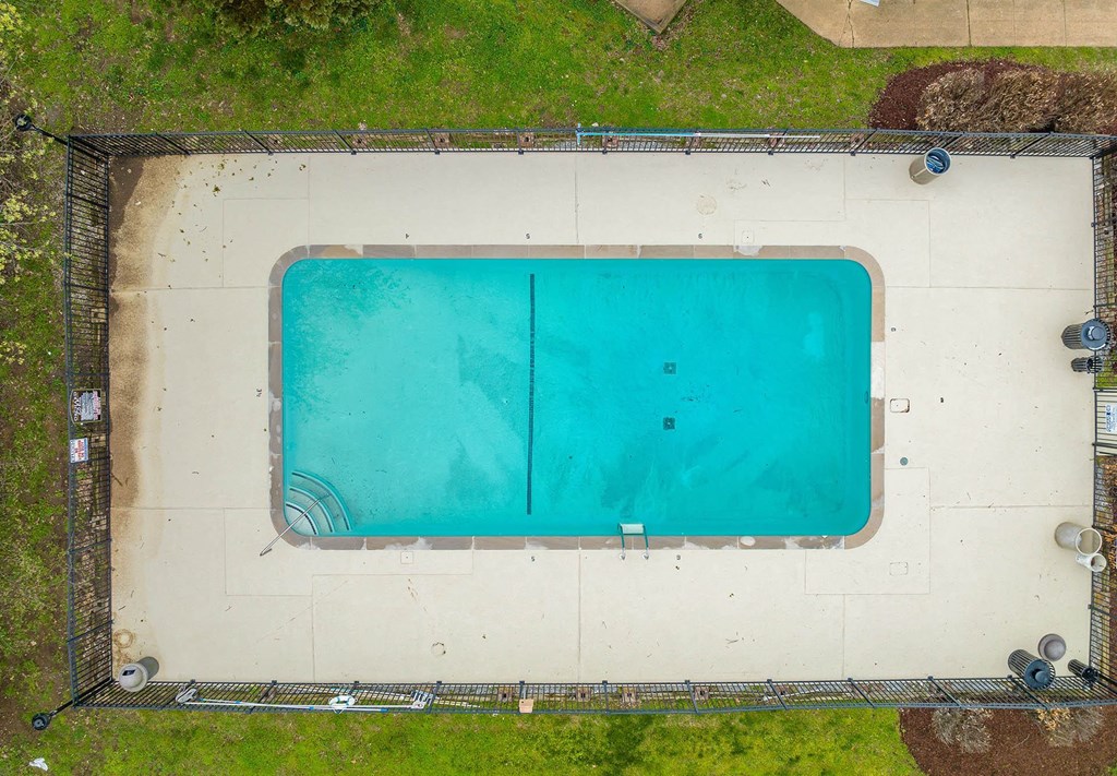 an aerial view of a swimming pool with green grass around it