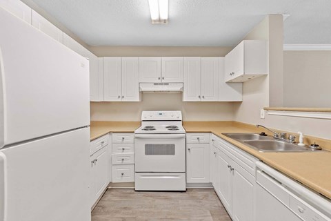 A white kitchen with a refrigerator, oven, and sink.