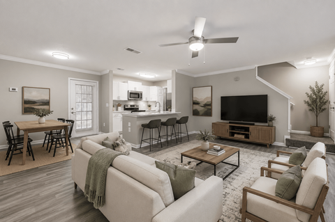 A well-lit living room with a couch, chairs, and a television.