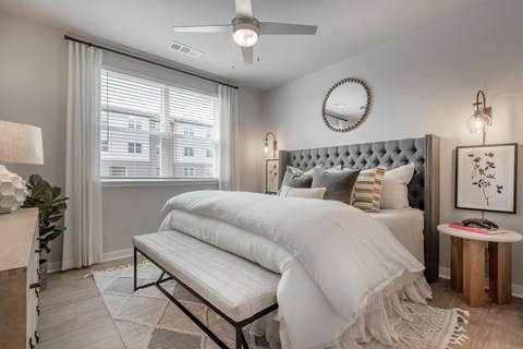 A bedroom with a large bed and a window with curtains.