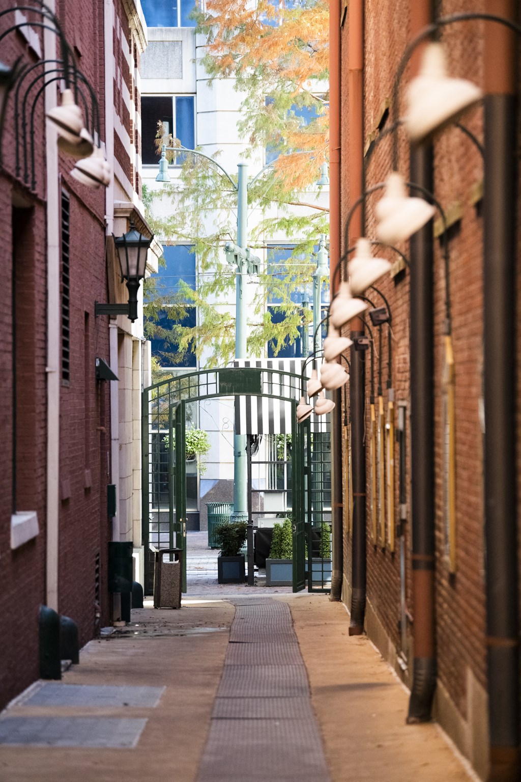 a city alleyway with red brick buildings and a gate