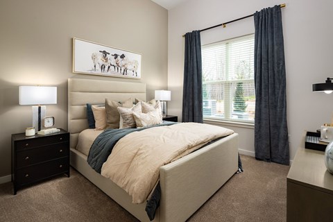 Pet-Friendly Luxury Apartments in Cumming, GA - Aura Creekside - A Modern Bedroom With Upholstered Bed, Neutral Bedding, And Matching Nightstands.