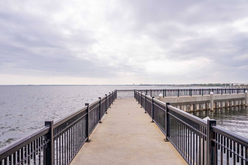 A long pier with a railing on both sides extends into the water.