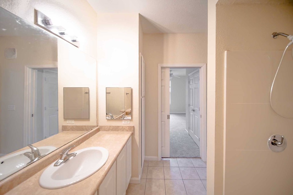 A bathroom with a sink, mirror, and shower.