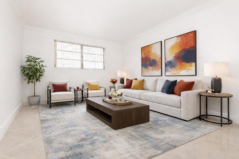A living room with a white couch, a coffee table, and two paintings on the wall.