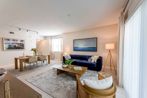 A living room with a blue couch and a painting on the wall.