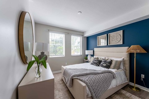 A bedroom with a large bed and a round mirror on the wall.