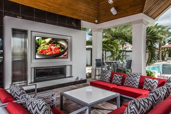 a tv mounted on the wall of a patio with furniture and a pool in the background - Photo Gallery 9