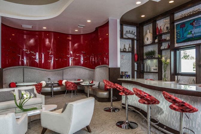 a restaurant with a red wall and white furniture at Altis Kendall Square, Florida 