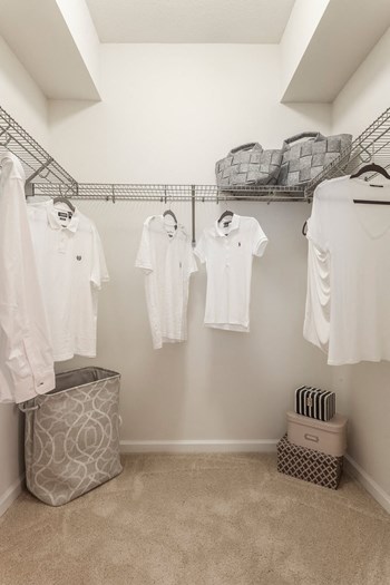 a walk in closet with white shirts hanging on the wall and a basket on the floor - Photo Gallery 18