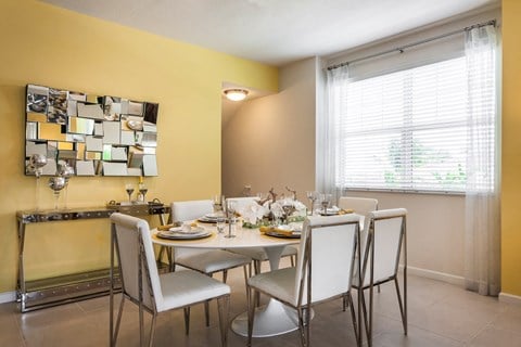 a dining room with yellow walls and a white table and chairs at Altis Kendall Square, Miami Florida