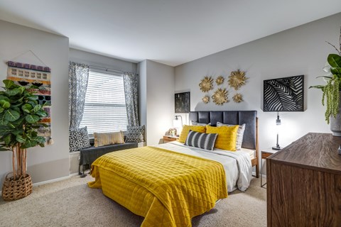 A bedroom with a yellow bedspread and a grey bed.