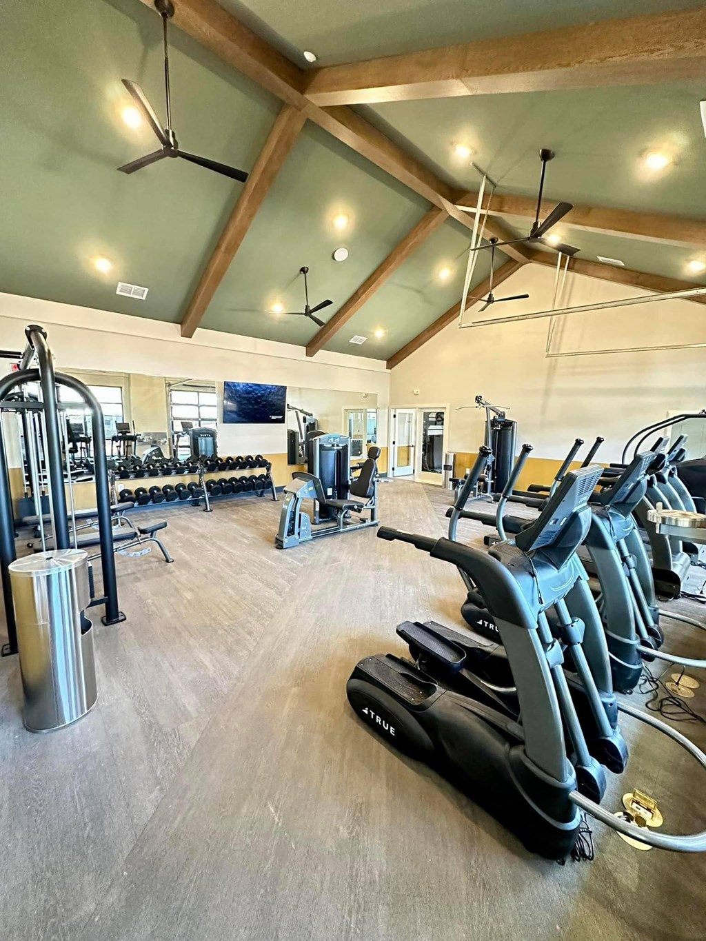 a gym with cardio equipment and weights on a wood floor