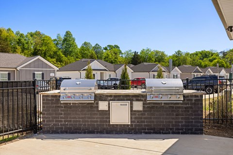 A row of houses with a brick wall and grills in front.
