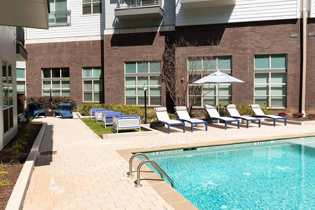 a swimming pool with lounge chairs and a building in the background