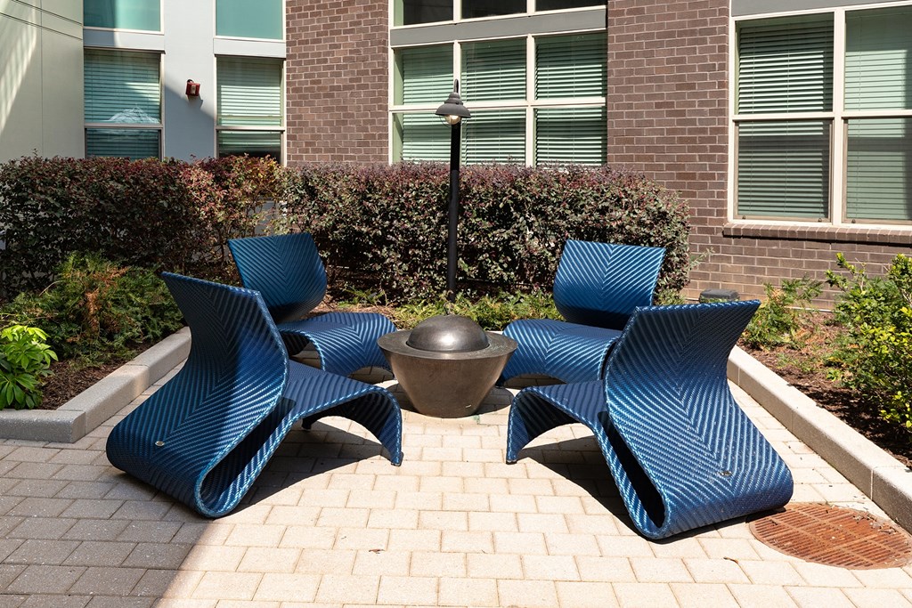 an outdoor seating area with blue chairs and a fire pit