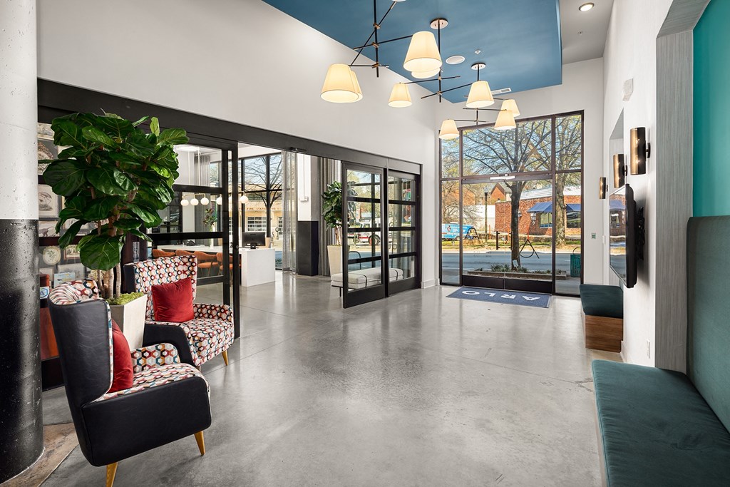 a lobby with chairs and a plant and glass doors