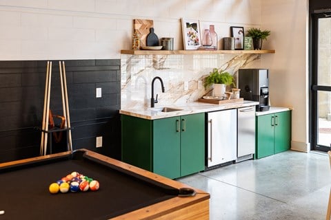 a kitchen with green cabinets and a pool table