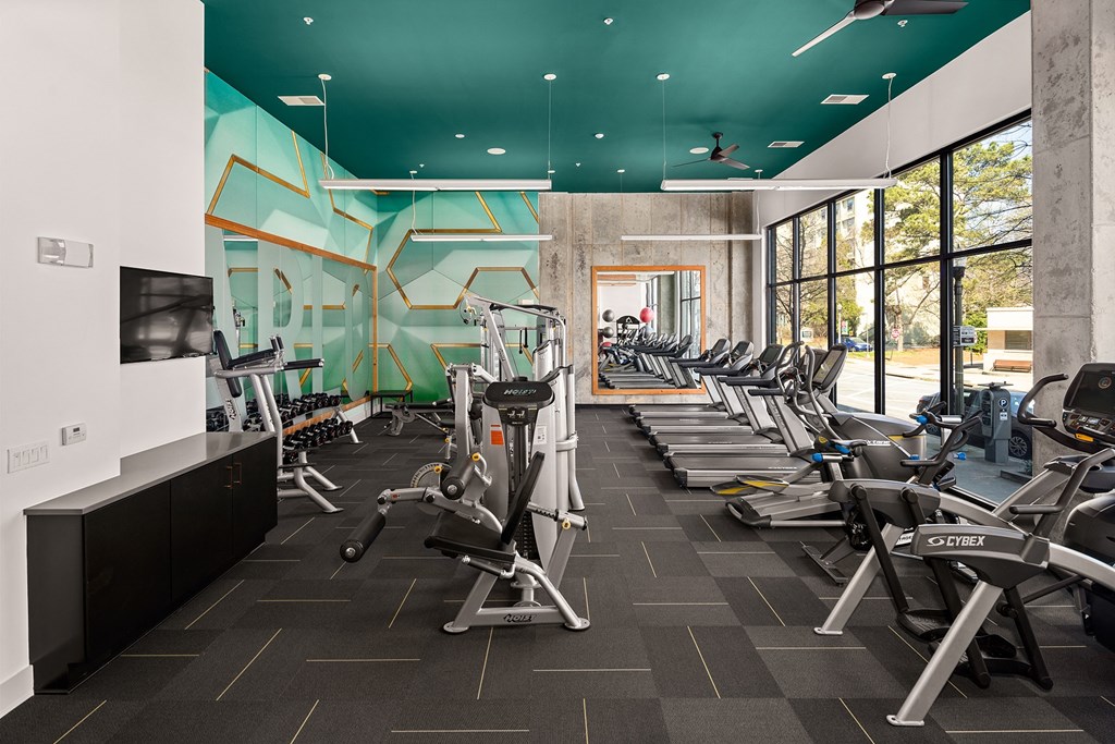 a gym with cardio machines and a wall of windows