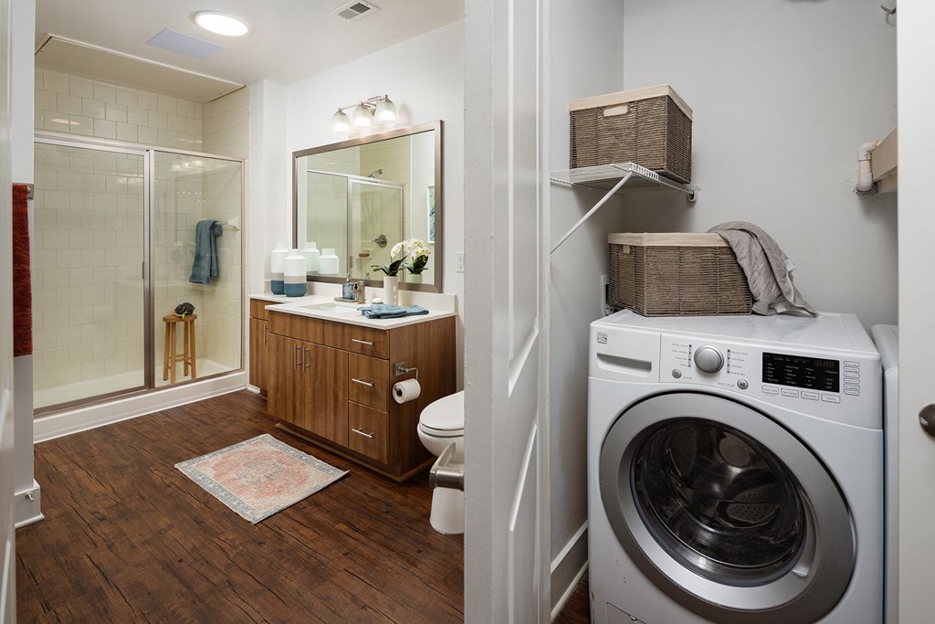 a bathroom with a washing machine and a toilet and a shower