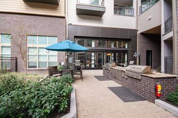 a patio with a grill and a table with chairs and an umbrella