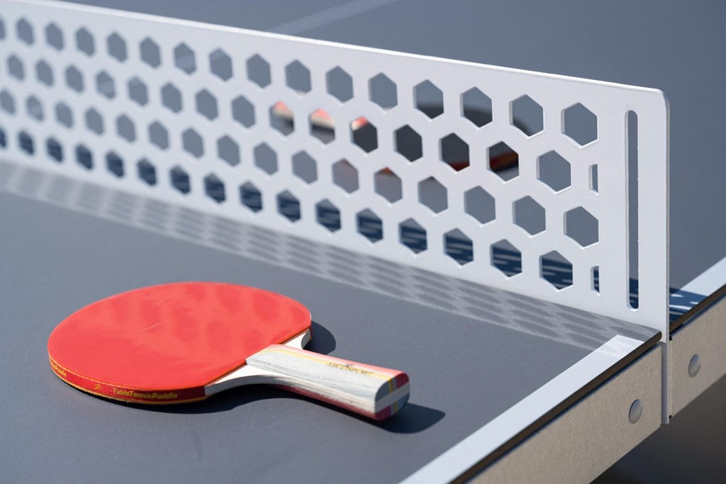 a red ping pong paddle on a table next to a net