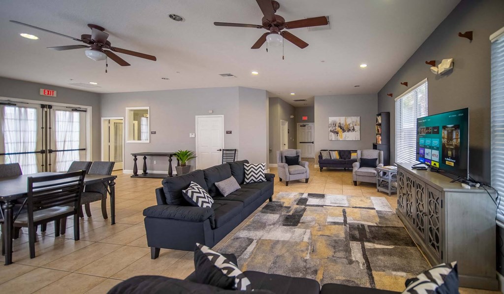 A living room with a ceiling fan and a rug on the floor.