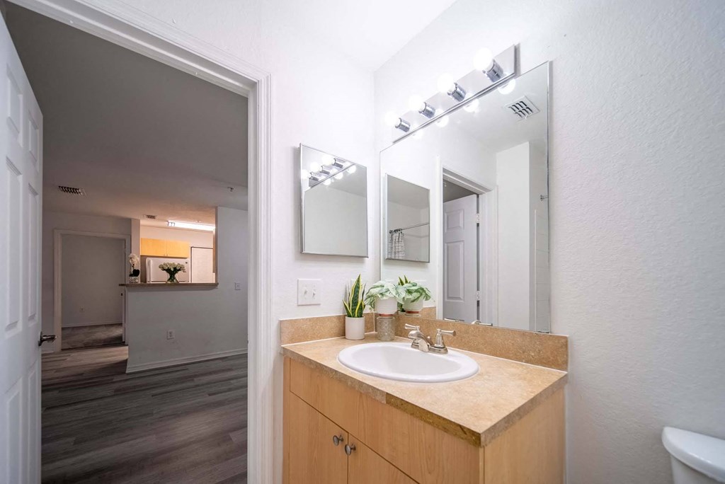A bathroom with a sink, mirror, and wooden cabinet.
