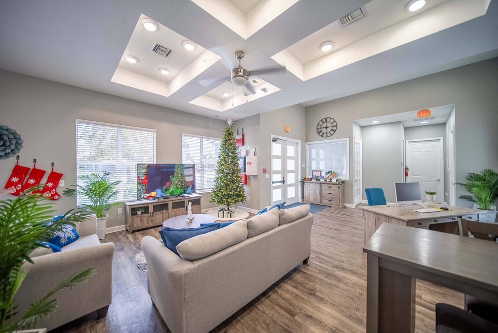 A living room with a couch, a Christmas tree, and a ceiling fan.