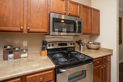 A kitchen with a stove, oven, microwave and cabinets.