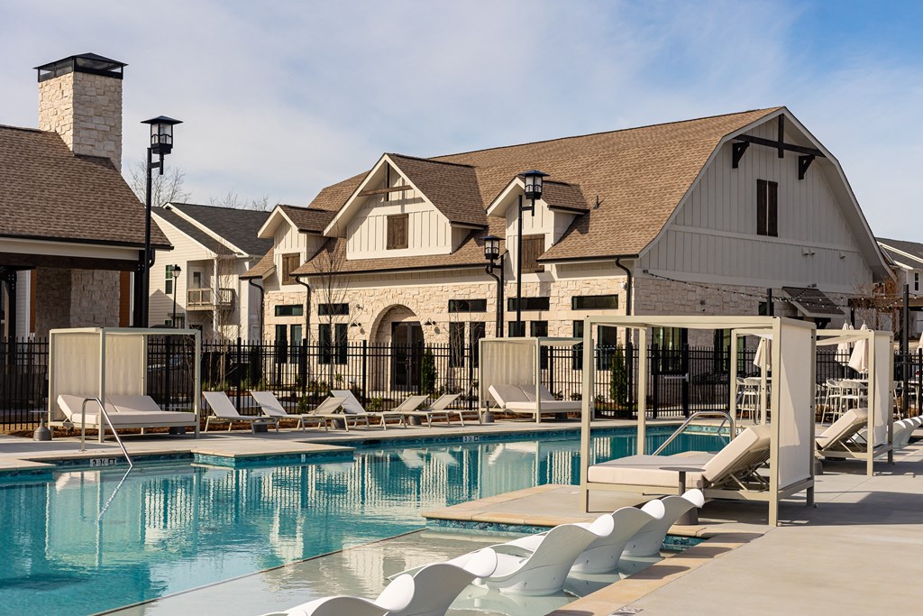 a swimming pool with lounge chairs in front of a building