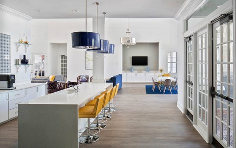 a long kitchen with a long white counter and yellow chairs