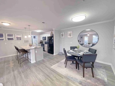 A dining room with a table set for two and a kitchen area in the background.
