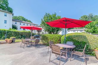 a patio with tables and umbrellas at the whispering winds apartments in pearland, tx