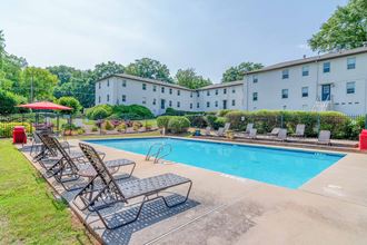 a swimming pool with chaise lounge chairs and a building in the background