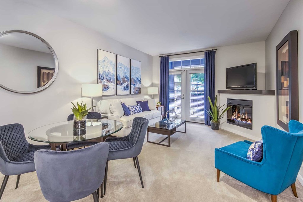 A living room with a fireplace, a blue chair, and a glass table.