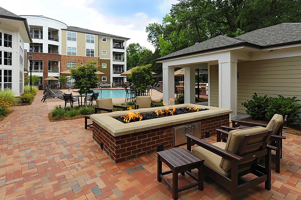 A patio with a fire pit and chairs.