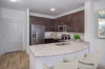 A kitchen with a granite countertop and two chairs.