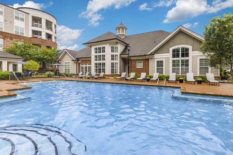Two-Bedroom Apartments in Charlotte, NC - Gramercy Square at Ayrsley - Swimming Pool with White Loungers, Small Tables, and Umbrellas, Overlooking the Apartments.